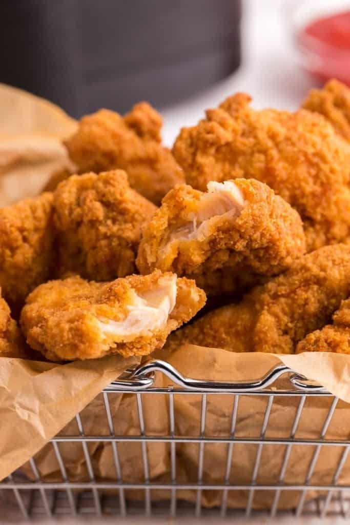 Closeup of chicken tenders in a wire basket with parchment paper