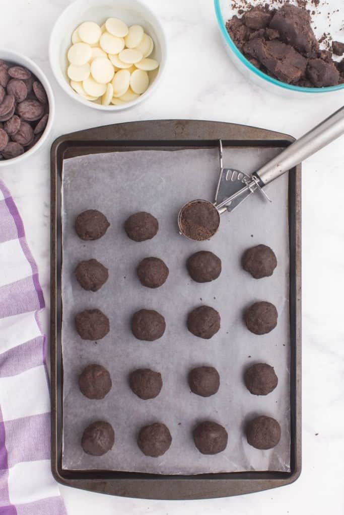 Oreo Balls without cream cheese being added to a baking sheet with parchment paper