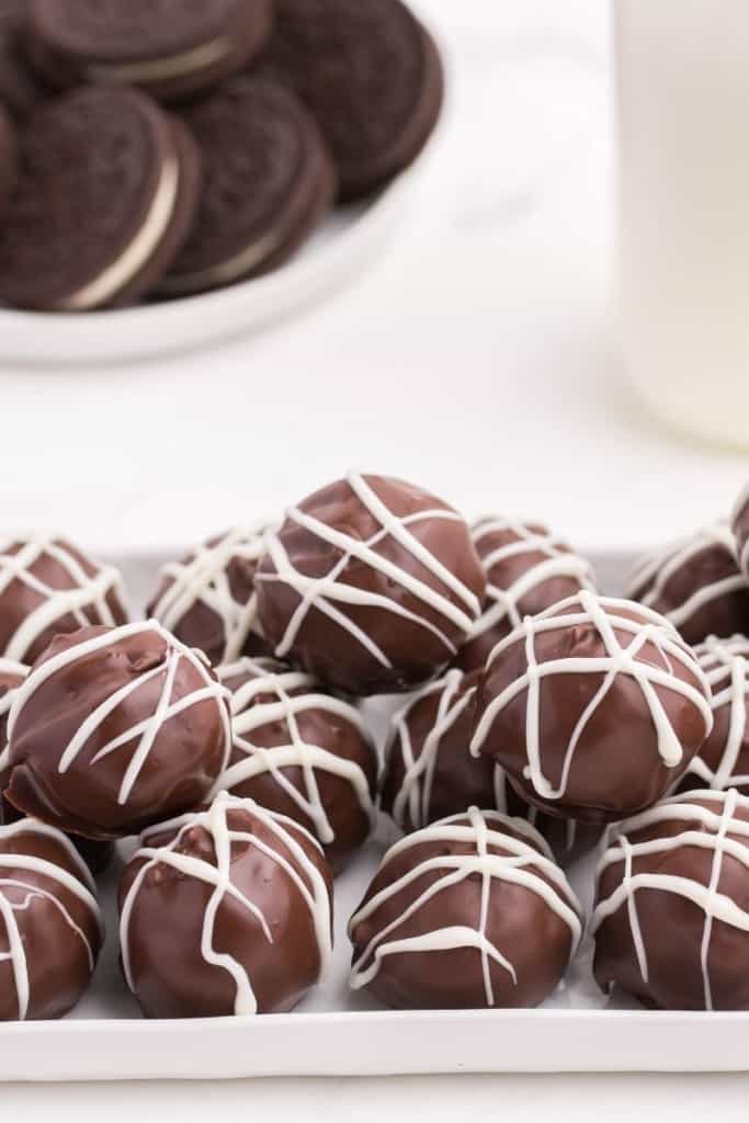 Oreo balls on a white plate with extra Oreos in background