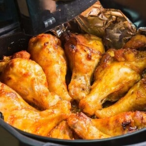 Wings being reheated in the air fryer with sauce on them and aluminum foil underneath