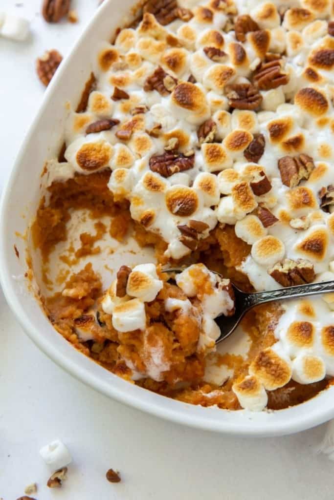 Closeup of sweet potato casserole in serving dish with serving spoon inside