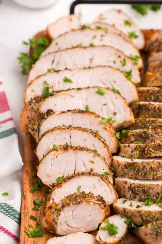 Closeup of sliced air fryer turkey breast tenderloins on a wooden serving tray