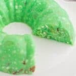 Lime jello salad with cottage cheese on a serving plate with a few pieces missing.