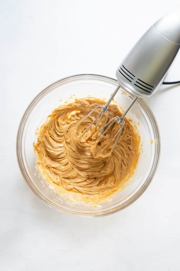 Peanut Butter Frosting being mixed by a hand mixer in a bowl