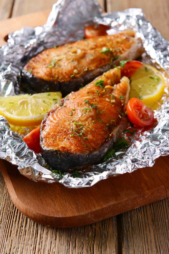 Fish wrapped in tin foil with fresh lemons and tomatoes