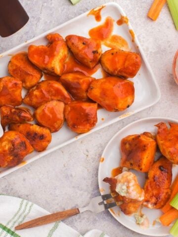 Air Fryer Boneless wings on a rectangle serving plate and some on a plate with fork inside one of the wings