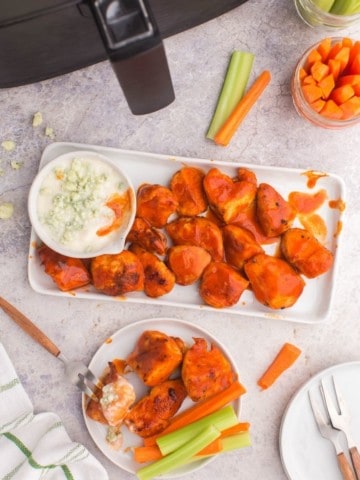 Air Fryer Boneless Wings on a rectangle serving platter covered with buffalo sauce and paired with blue cheese and carrots/celery