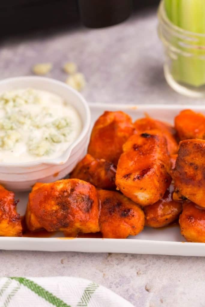 Closeup of boneless wings on a rectangular platter with blue cheese in a bowl