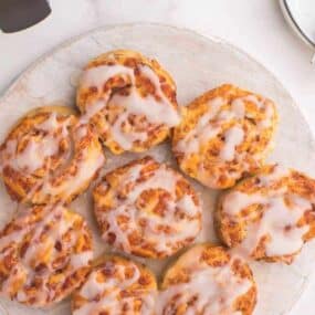 Air Fryer Cinnamon Rolls with icing on them on top of a round white plate