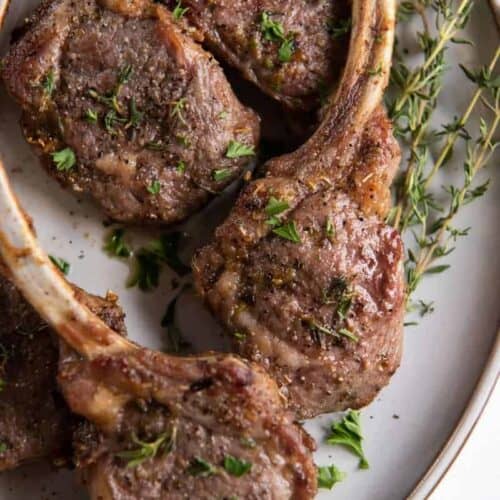 Air Fryer Lamb Chops on a plate with oregano and rosemary on top