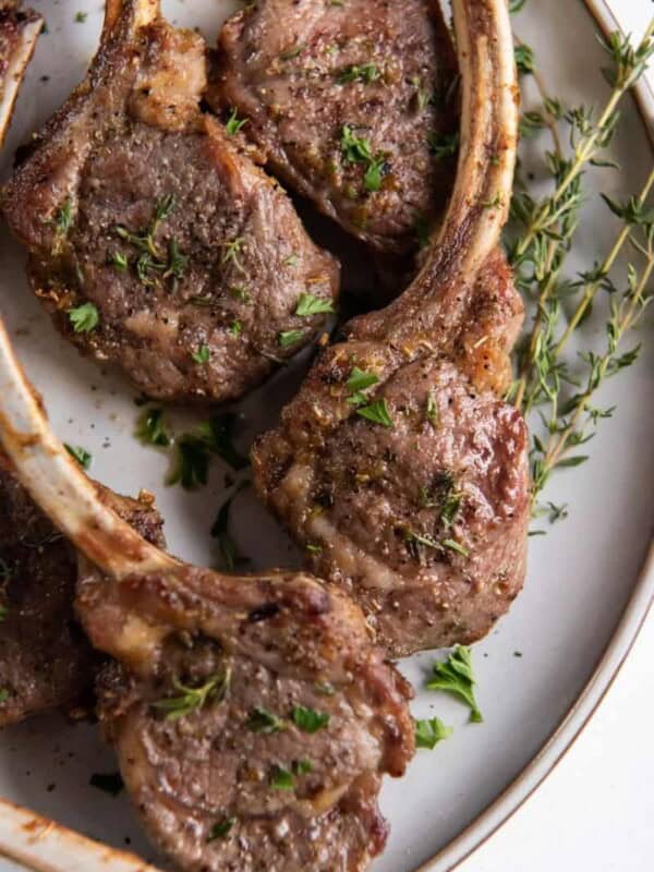 Air Fryer Lamb Chops on a plate with oregano and rosemary on top