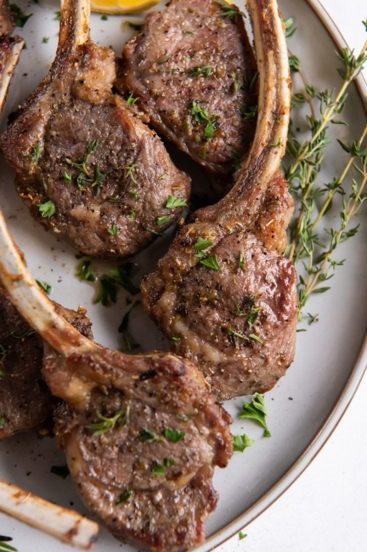 Air Fryer Lamb Chops on a plate with oregano and rosemary on top