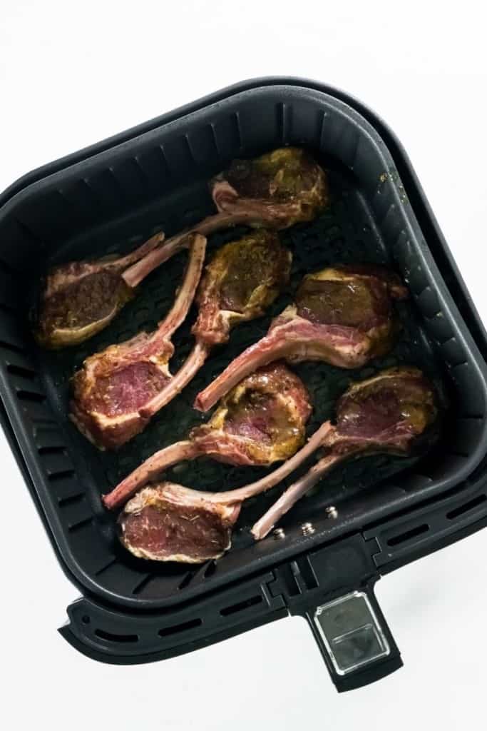 Raw lamb chops in air fryer basket in one layer