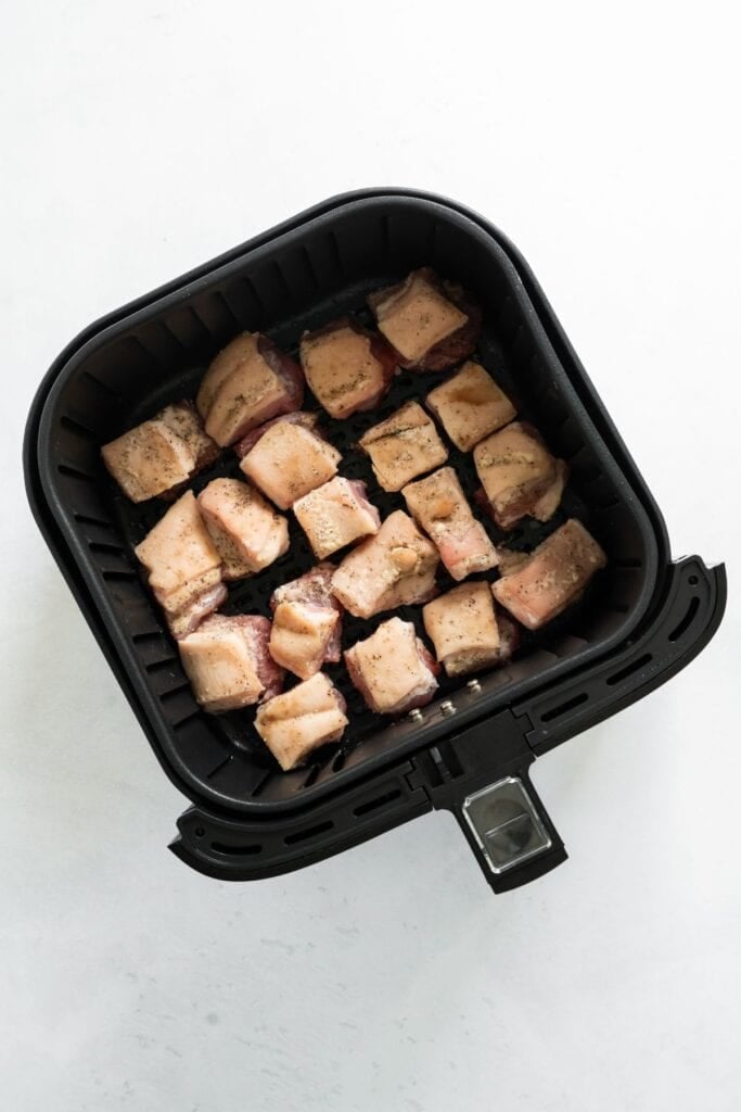 Raw pork belly in an air fryer basket.