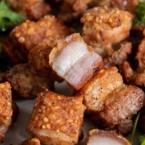 Air fryer pork belly bites that are golden brown and crispy on a plate.