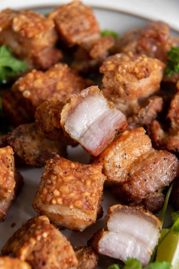 Air fryer pork belly bites that are golden brown and crispy on a plate.