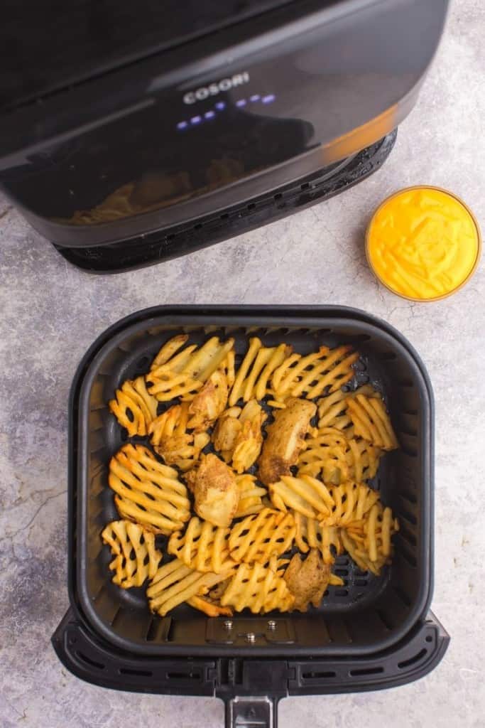 Frozen Waffle Fries in the air fryer cooked with a side of nacho cheese