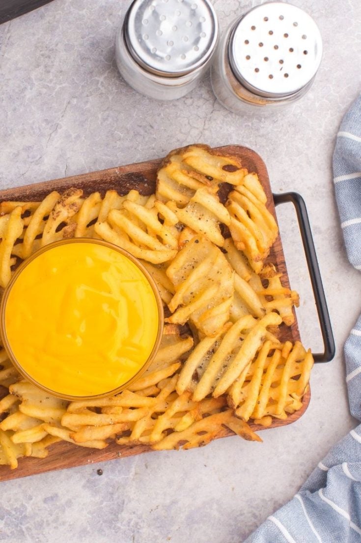 Air Fryer waffle fries on a serving tray with nacho cheese in the middle