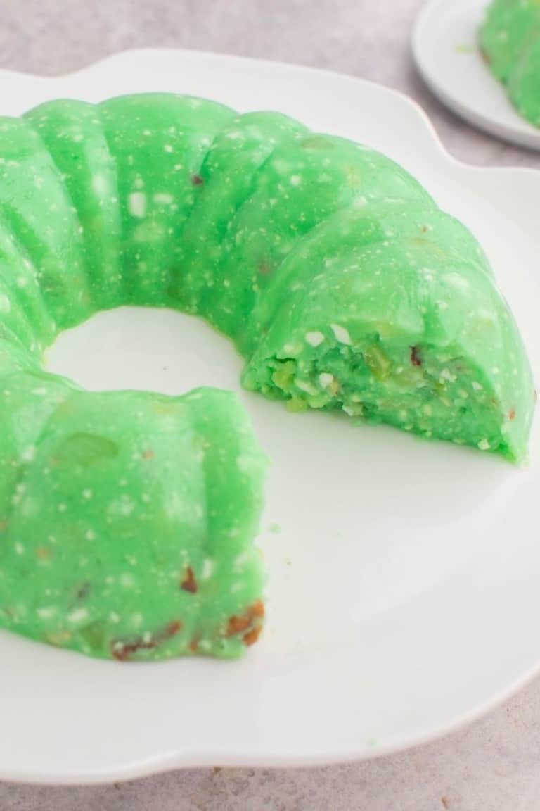 Lime Jello Salad with Cottage Cheese made in a bundt pan and flipped onto a white plate with piece cut out and missing