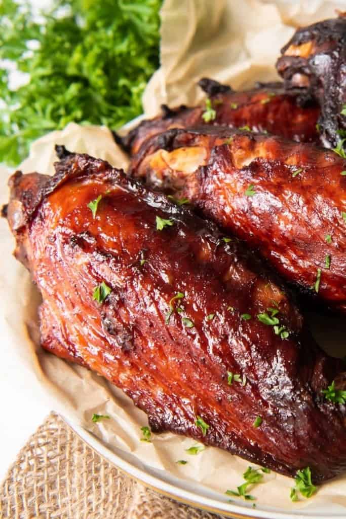 Turkey wings on a plate with parchment paper underneath of the wings