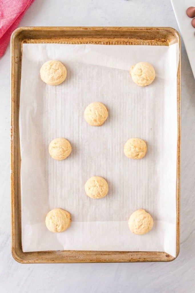 Cooked thumbprint cookies on a baking sheet with parchment paper