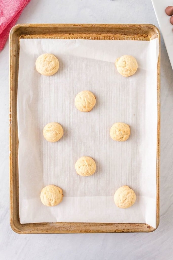 Cooked thumbprint cookies on a baking sheet with parchment paper