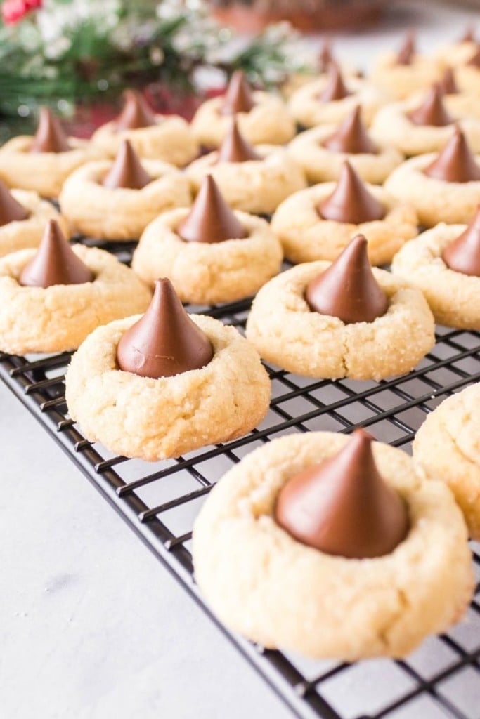 Blossom cookies without peanut butter on a black wired cooling rack with a Hershey kiss on the top of each