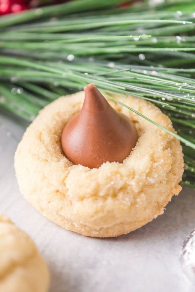 Closeup of a Christmas Hershey kiss shortbread cookie with green garland in the background