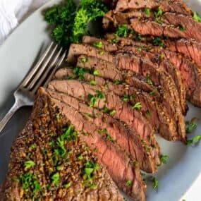 Air Fryer London Broil sliced on a serving plate with a fork and parsley topping it
