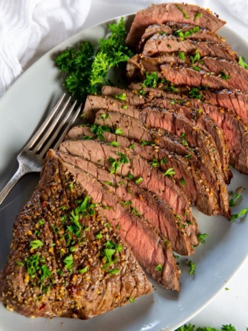 Air Fryer London Broil sliced on a serving plate with a fork and parsley topping it