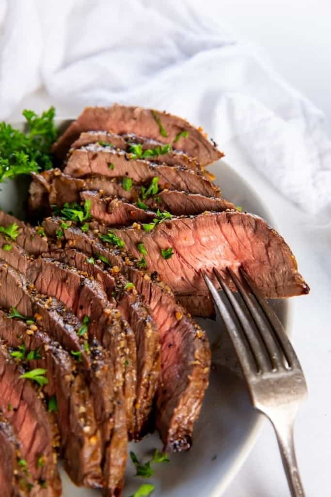 London Broil on a plate sliced with a fork inside a slice