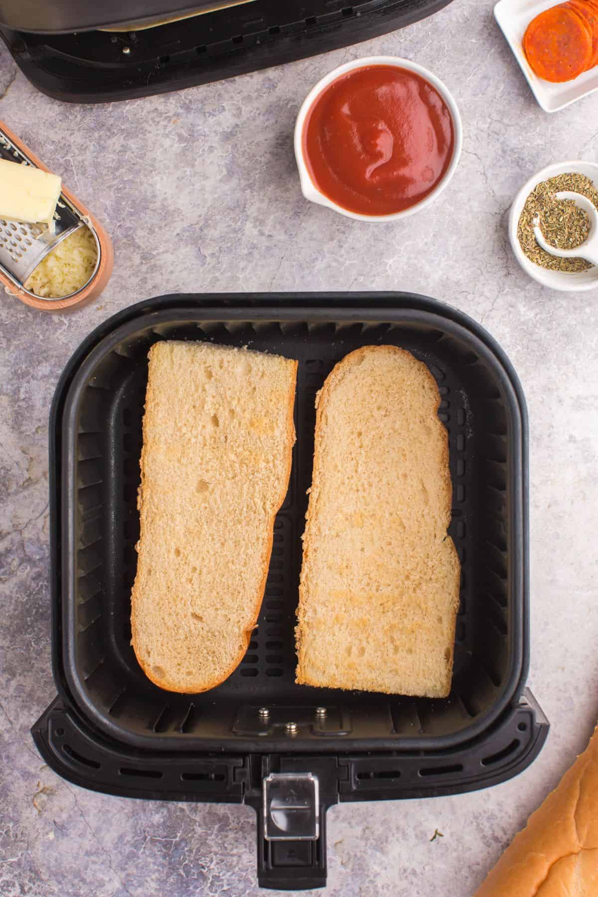 2 slices of french bread in an air fryer basket.