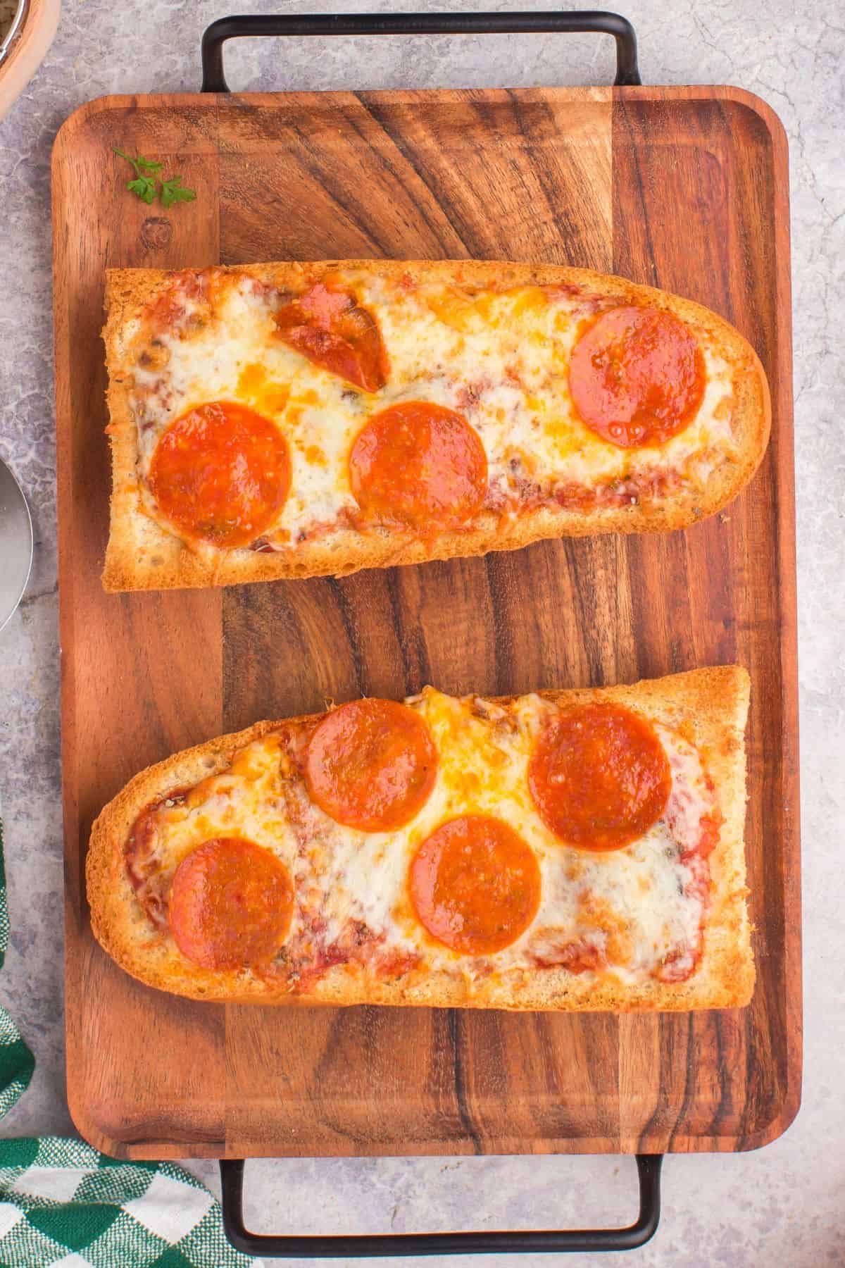 Close up of the air fryer french bread pizza on a wooden serving tray.