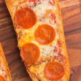 Air fryer french bread pizza with pepperoni on a wooden serving tray.