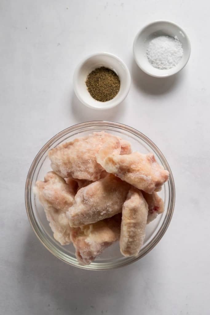 Frozen chicken wings and salt and pepper in different bowls