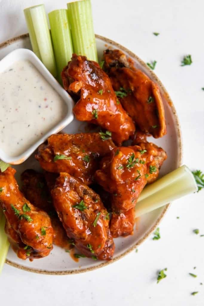 Buffalo chicken wings on a plate with blue cheese and celery