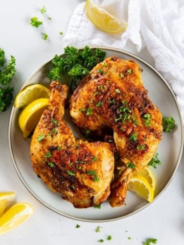 Air fryer chicken leg quarters with lemons on the side