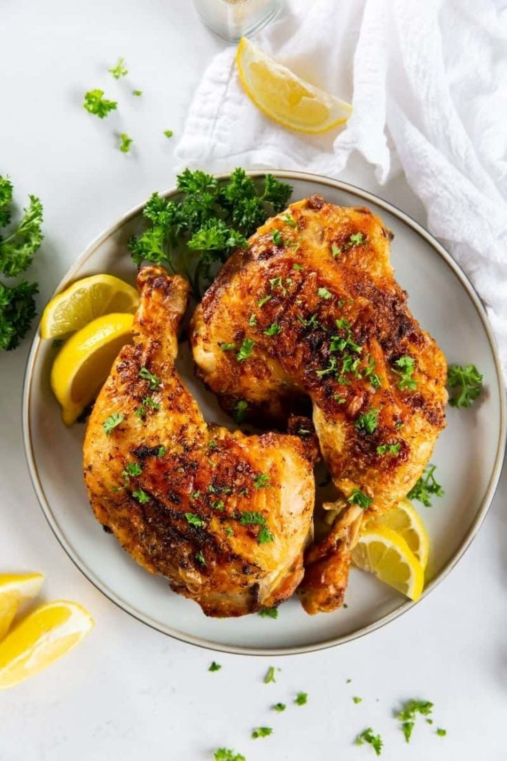 Air fryer chicken leg quarters with lemons on the side