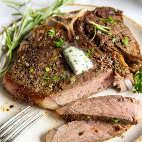 air fryer t bone steak on a white plate, cut into.