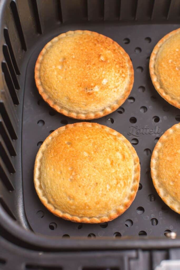 Closeup of air fried uncrustables with a golden brown top inside the air fryer basket.