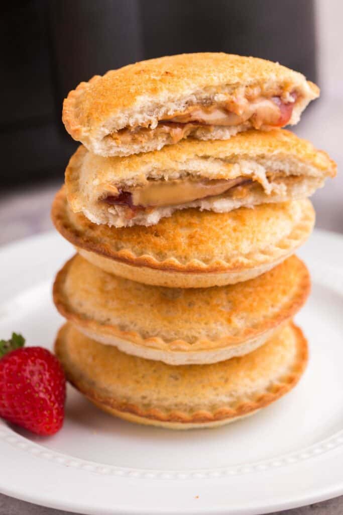 Stacked air fryer Uncrustables on top of each other with the top one split in half.