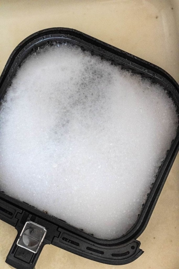 Air fryer basket and drawer being soaked in water and Dawn dish soap