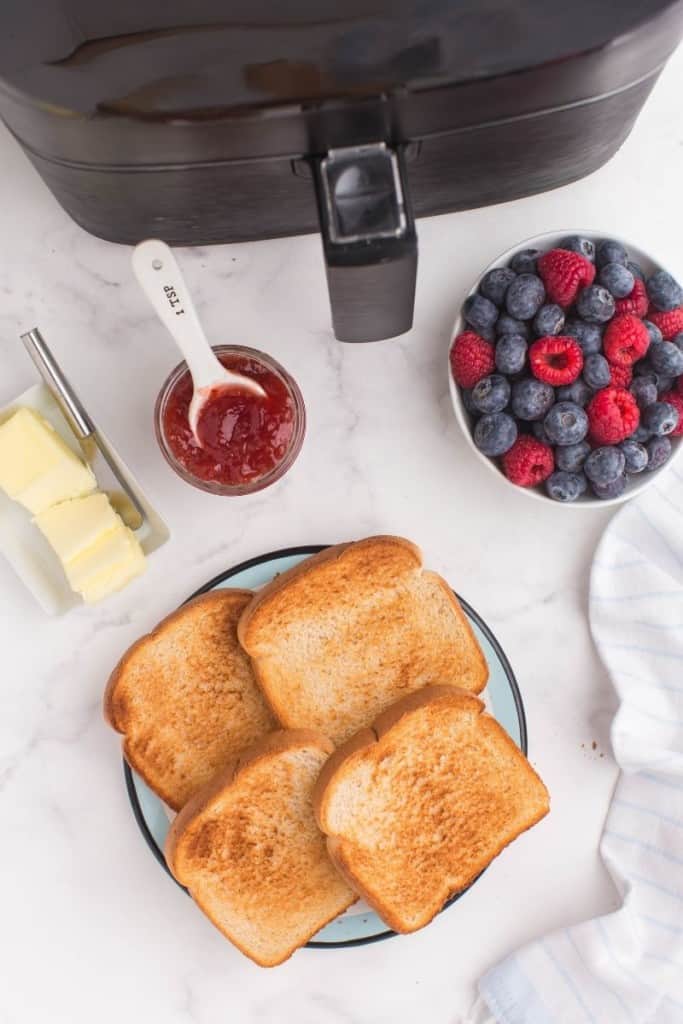 air fryer toast slices on plate with jam and berries on the side