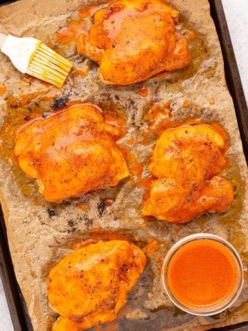 buffalo chicken thighs on cooking pan with parchment