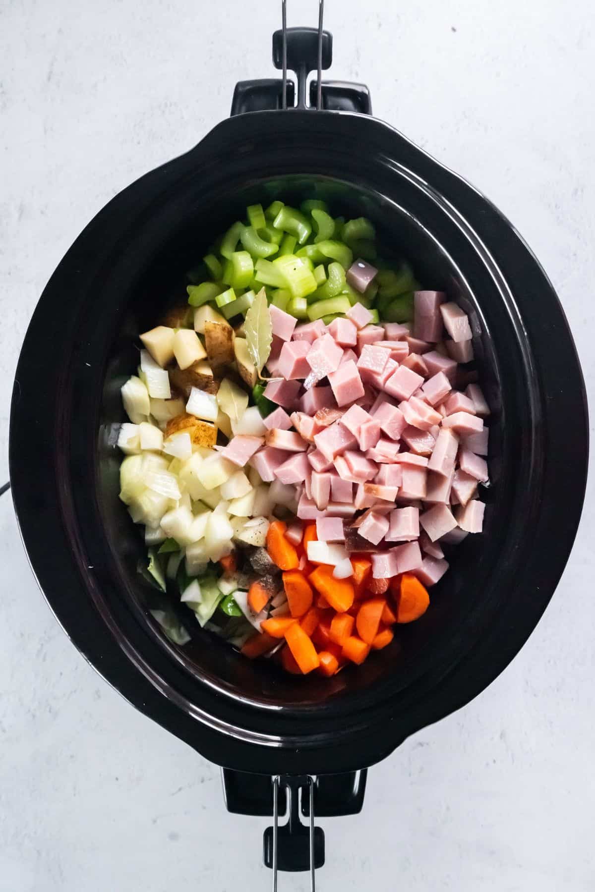 Ham and cabbage in the crockpot with all other ingredients about to be cooked.