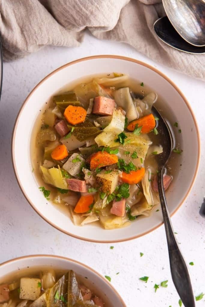 crockpot ham and cabbage soup in white bowl