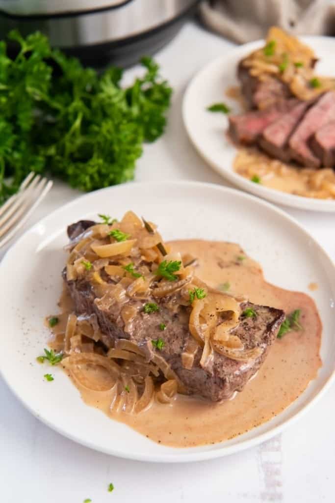 instant pot steak on plate with sauce drizzled on top