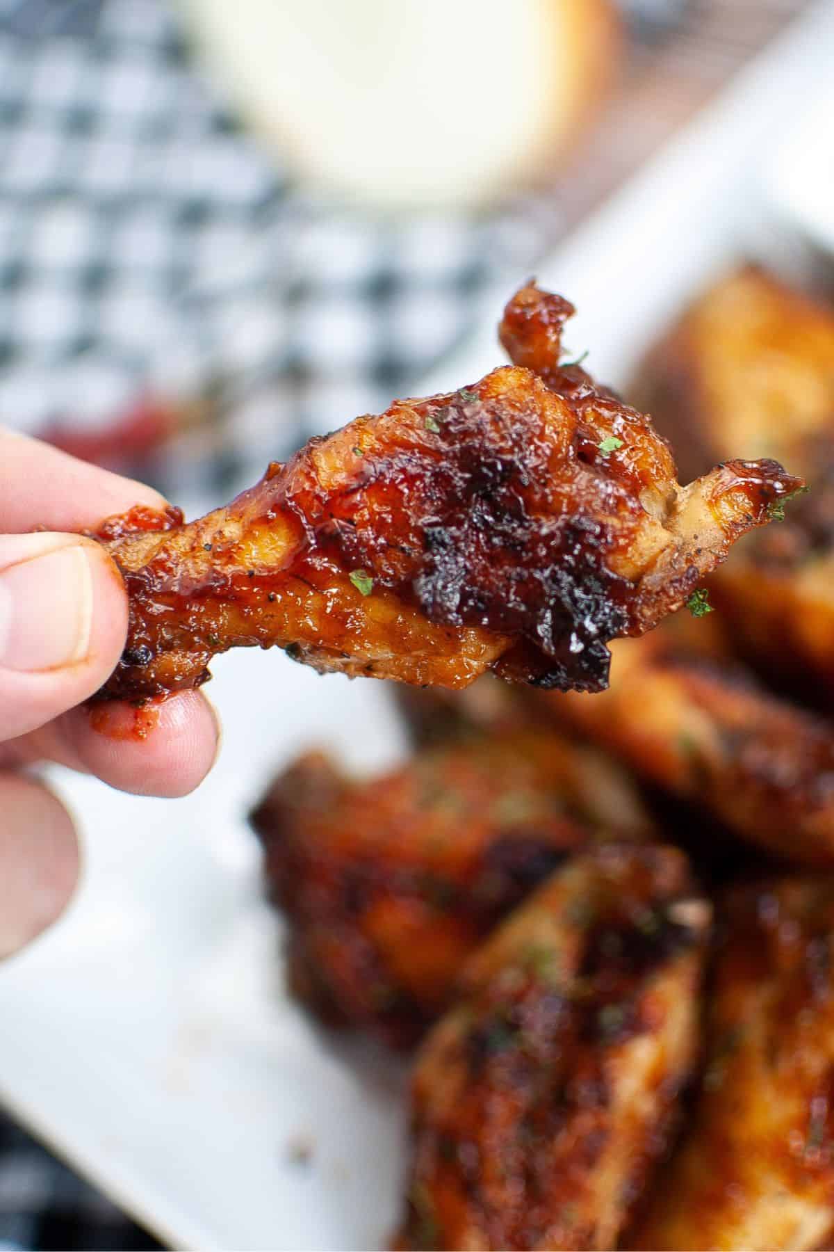 Air fryer bbq chicken wing being held.