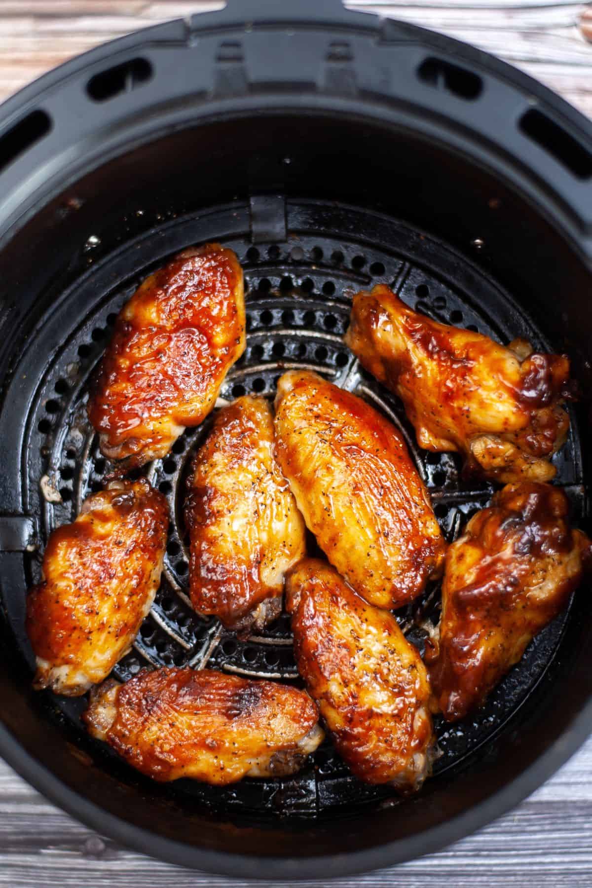 BBQ chicken wings in an air fryer basket.