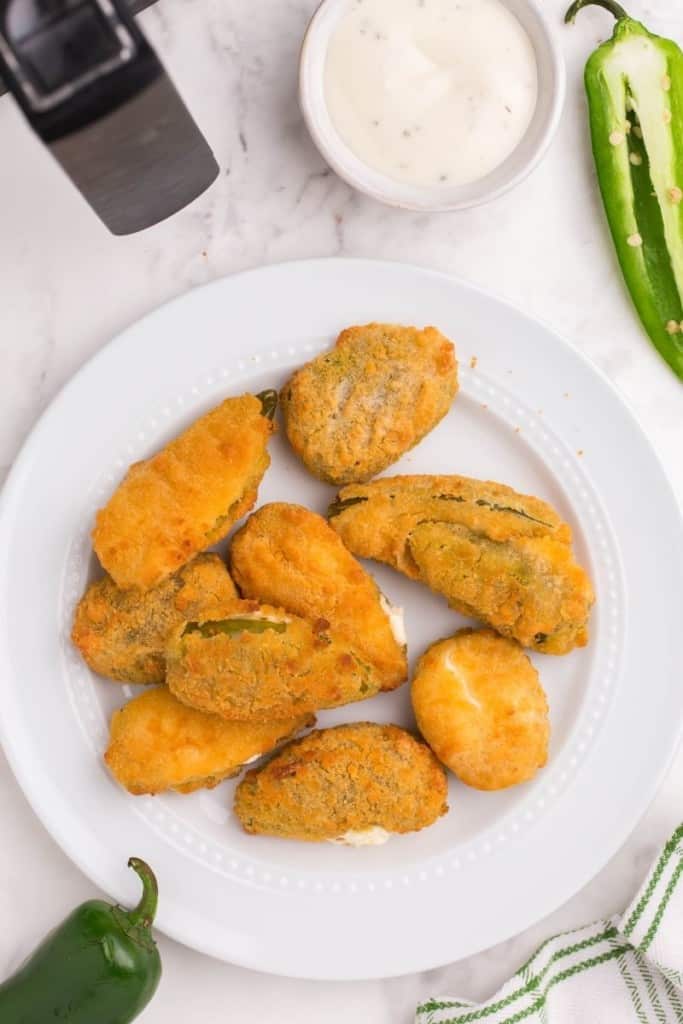 jalapeno poppers on white plate with dipping sauce on the side